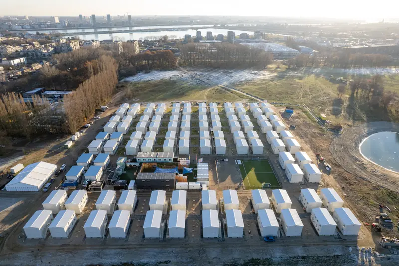 Luchtfoto van het afgewerkte nooddorp met de stad op de achtergrond